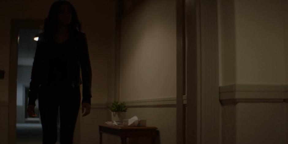Sophie walks down the hallway towards Alia Nazari's apartment.