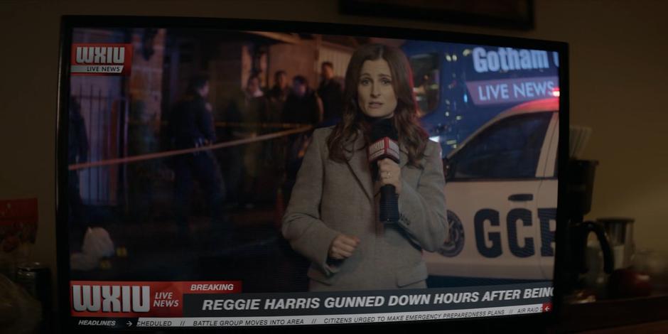 A reporter covers Reggie Harris's murder on the news.