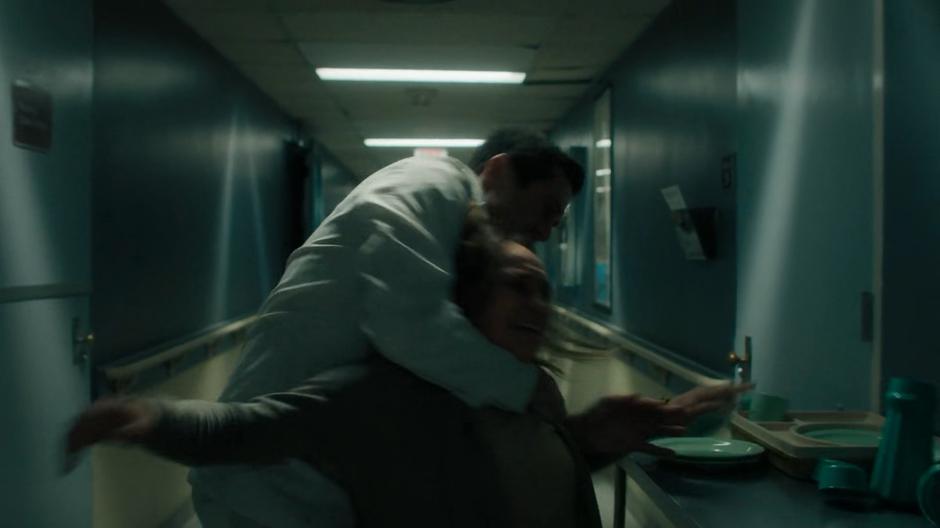 An orderly pulls a patient down the hallway away from Mel's room.