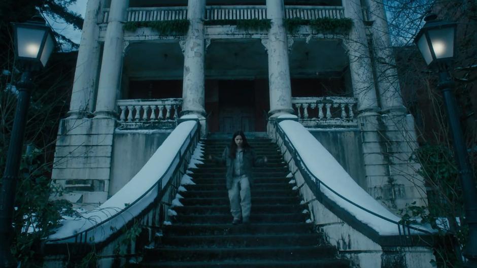 Mel runs down the stairs in front of the run down institute.