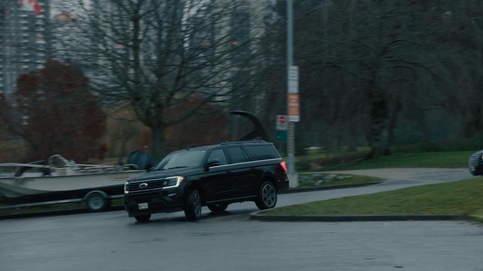 A pair of dark SUVs race into the driveway.