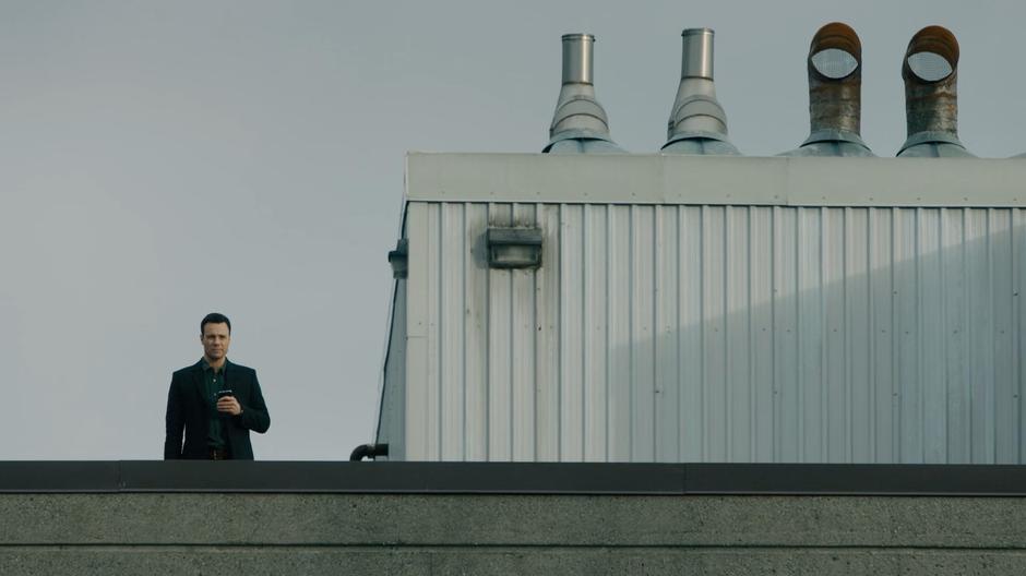 Harry spies on people arriving at the facility from a nearby rooftop.