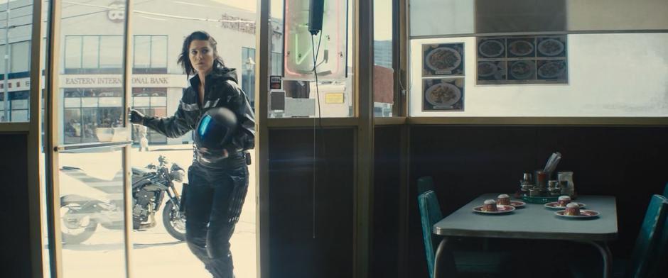 Helena enters the restaurant after parking her motorcycle outside.