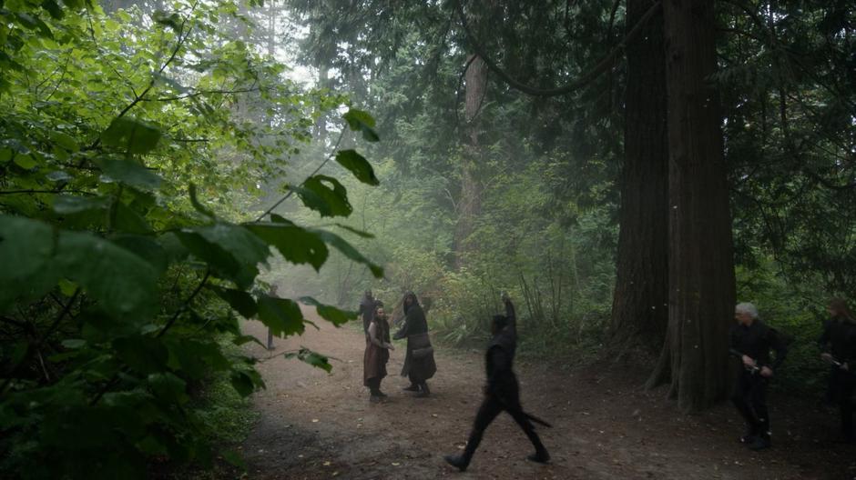 Julia and Eliot look around as guards emerge from the forest to surround them.