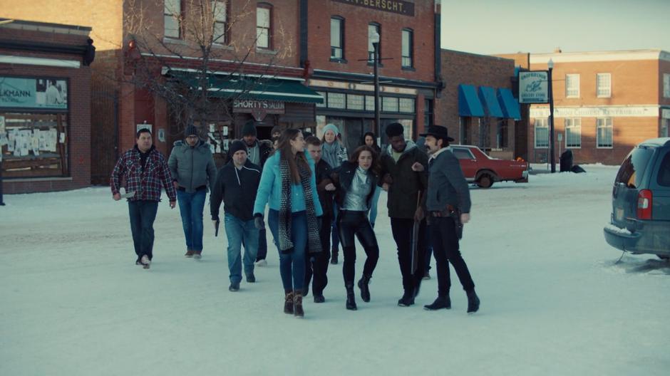 Chrissy and her posse pull Wynonna across the street towards the gallows while Doc argues with them.