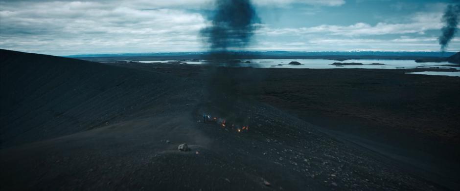 Smoke rises from Michael's crash site and the other crash site in the distance while she works with her suit.