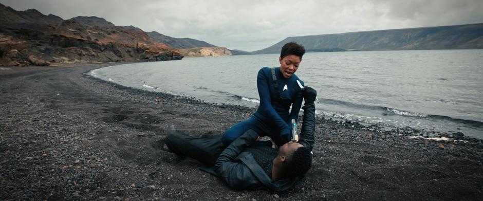 Michael kneels on Booker's chest pointer her phaser at his head while he holds his knife near her neck.