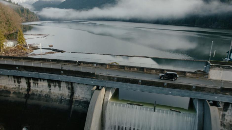 A car drives across the top of the dam.