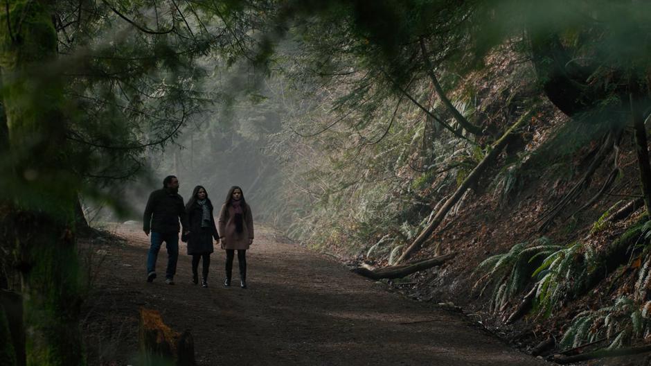 Ray, Mel, and Maggie talk while walking down the forested path towards the dam.