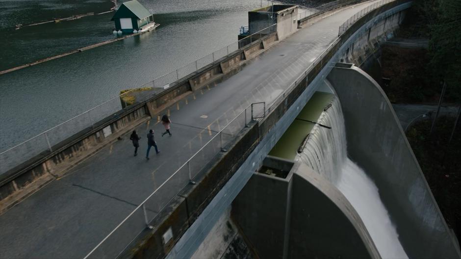 Maggie, Mel, and Ray run across the dam to the entrance.