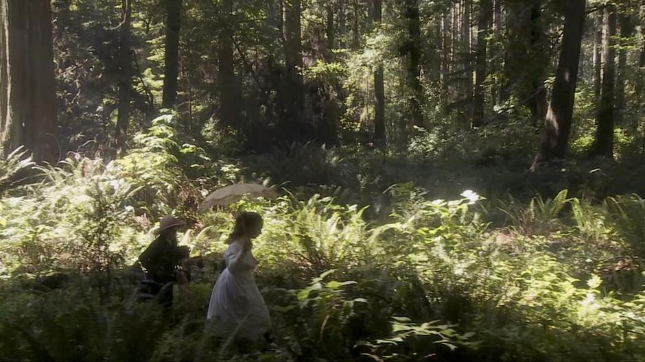 Katie and Sebastian run through the woods.