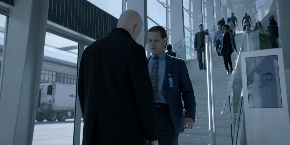 Victor Zsasz creepily steps up to a Hamilton employee walking through the lobby.