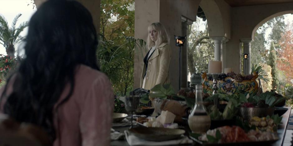 Alice warily circles Safiyah who has sat at a table full of food.