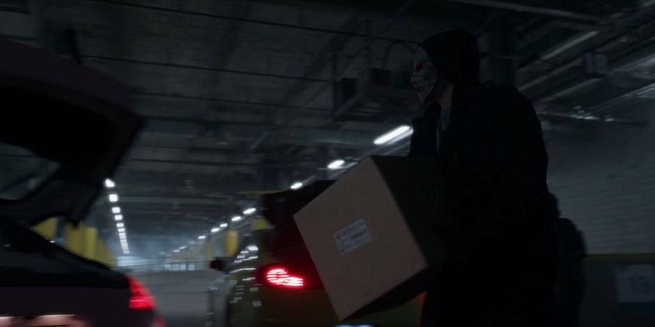 Members of the False Face Society put boxes into the trunks of the cars.