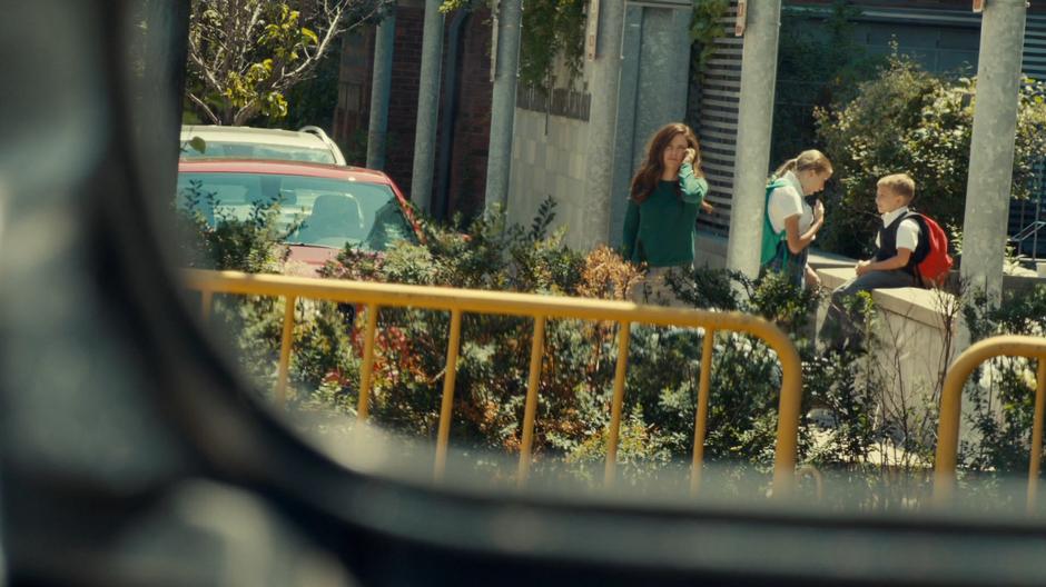 Mary stares at the suspicious car while calling Ben on the phone.