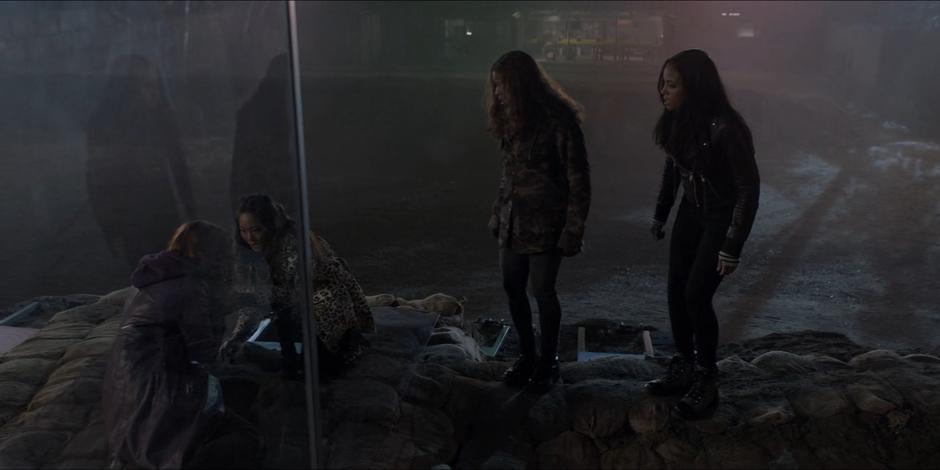 Mary kneels down to examine Stephanie Brown as Ryan and Sophie watch.