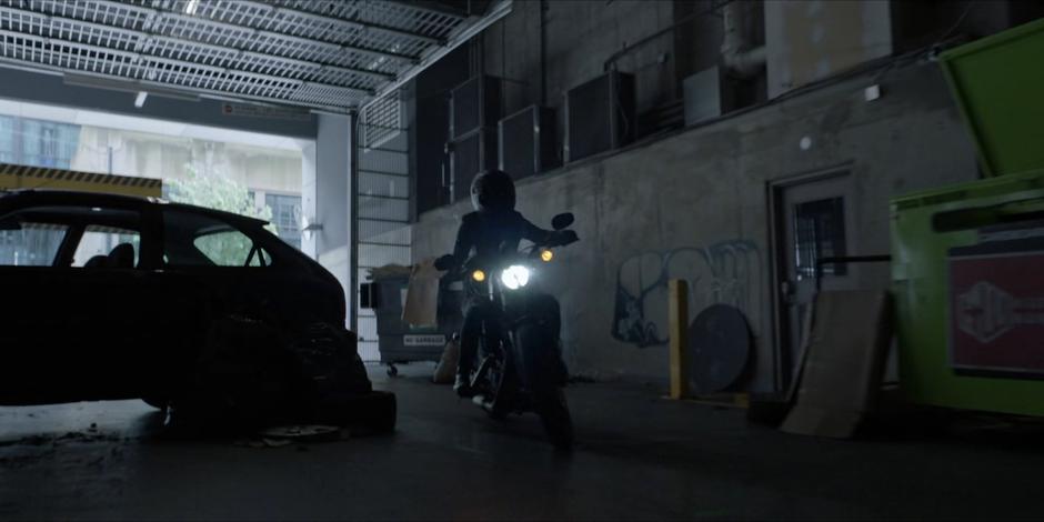 Kate pulls into the abandoned loading dock on her motorcycle.