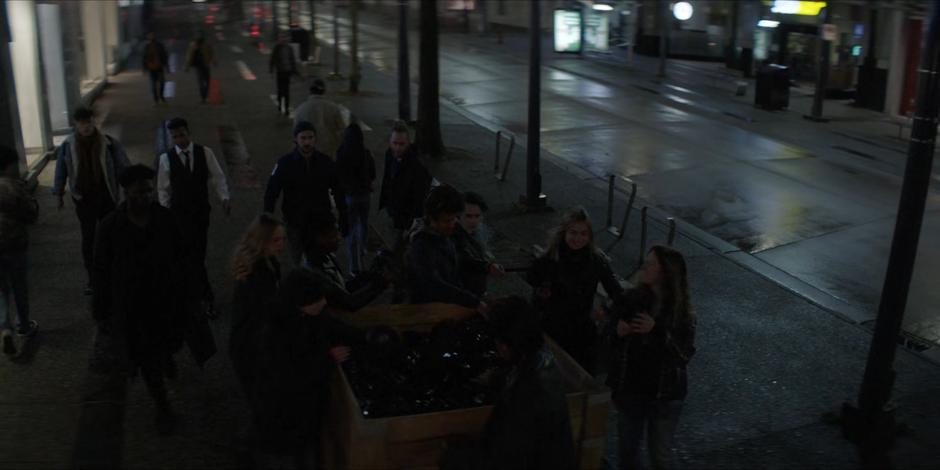 People grab masks from a box left on the street.