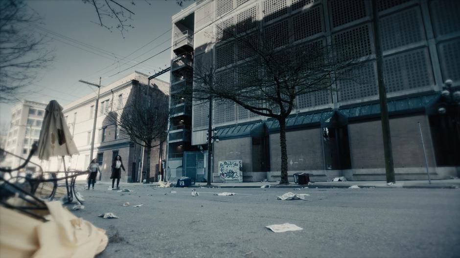 Maggie and Macy look around the desolate street after fleeing the attack at SafeSpace.