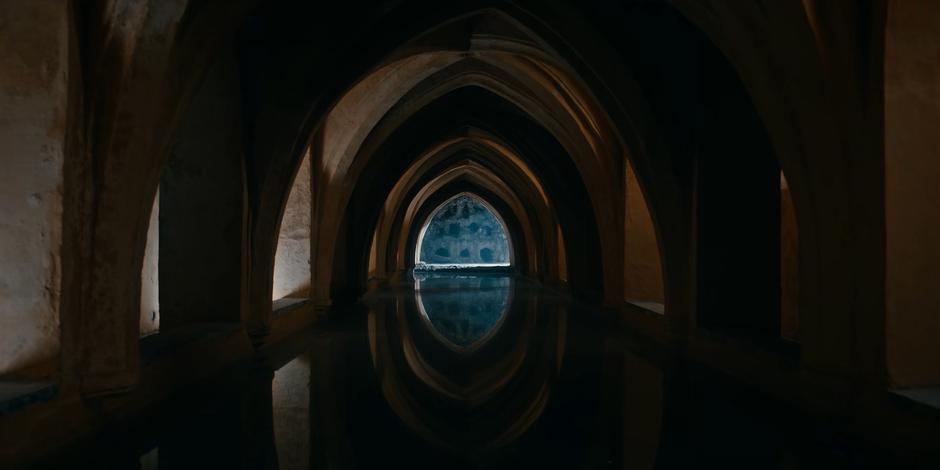 A still pool of water lies beneath the arches of the catecombs.