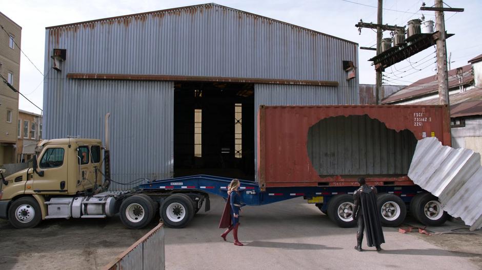 Kara approaches J'onn as he examines the ripped-open container.