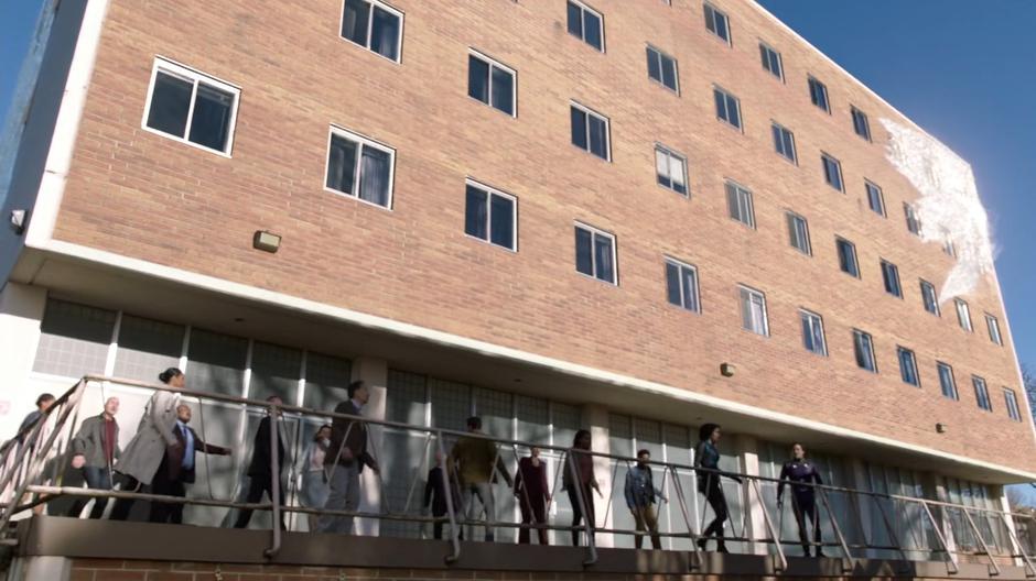 The people from inside gather on the balcony as the ice gathers on the building.