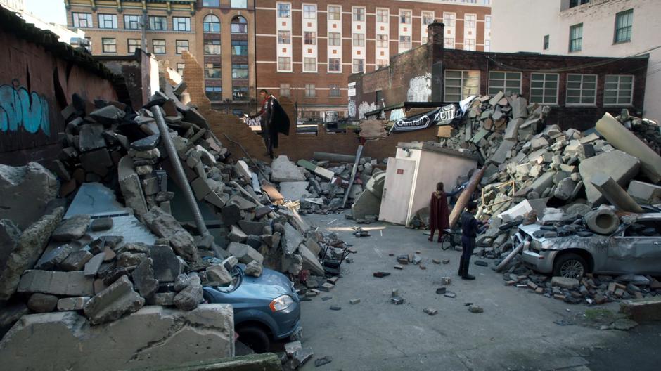 J'onn, Kara, and Brainy scan the rubble for 5th-dimensional energy.