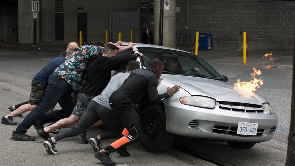 People under the influence of the Humanity Totem try to flip a car with someone inside.