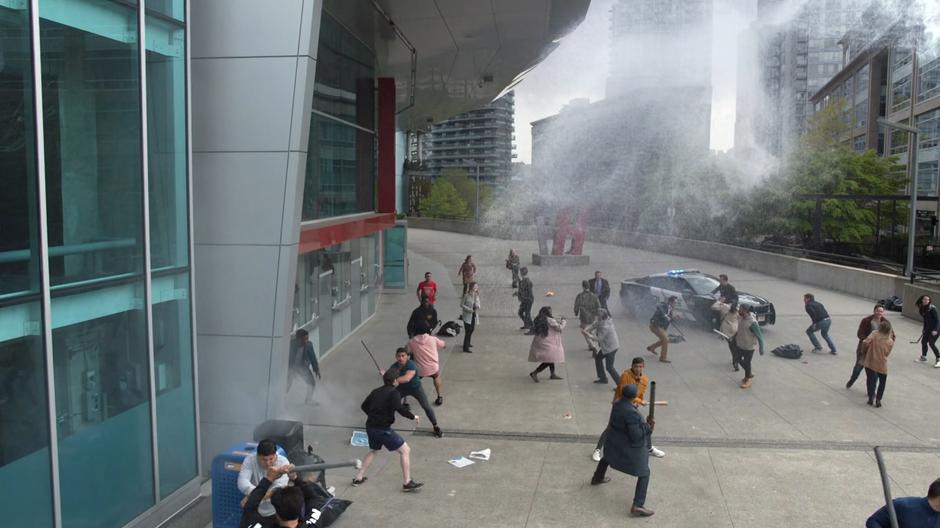 A large crowd of people fight outside the stadium.