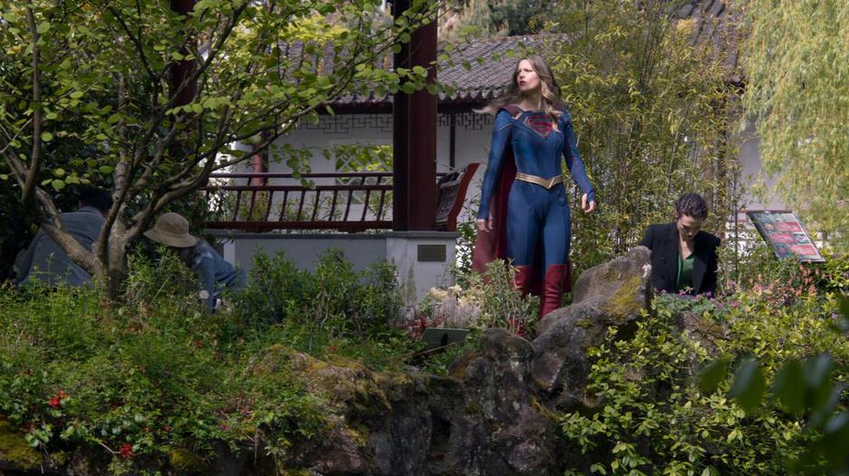 Kara keeps an eye out for interruptions as Lena gathers the plants she needs for the spell.