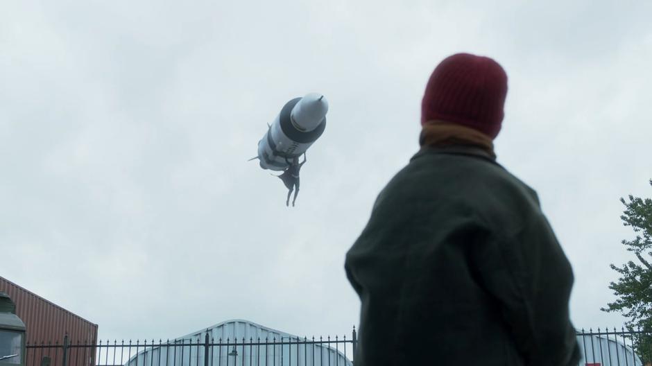 A young girl looks up at Kara as she stops a missile from exploding.