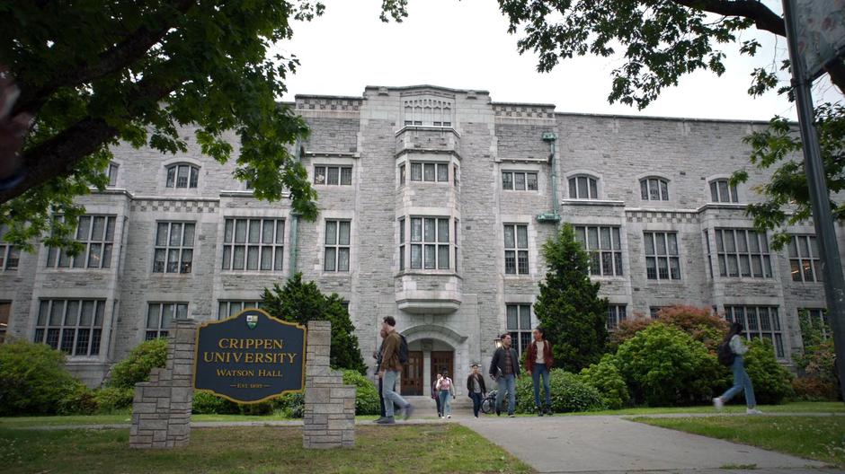 Students walk along paths outside near a sign that says "Crippen University, Watson Hall".