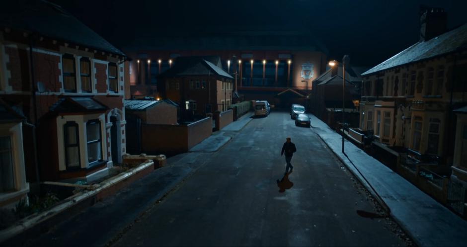 Dan crosses the street at night towards his house.