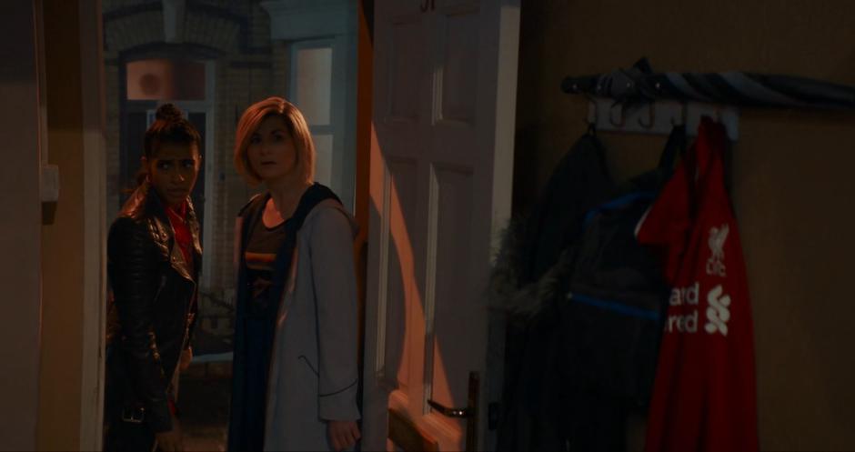 Yaz and the Doctor look in through the open door of Dan's house.