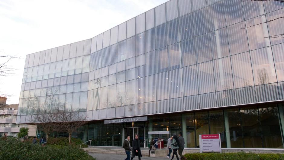 Establishing shot of the exterior of the building with students walking past.