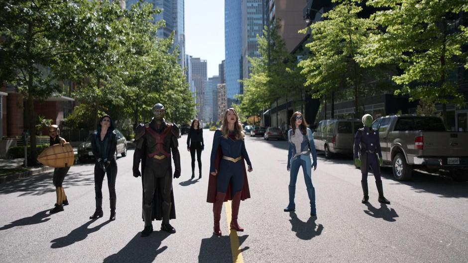 Kelly, Alex, J'onn, Lena, Kara, Nia, and Brainy look up from where they are assembled as their opponents call in their old foes for reinforcements.