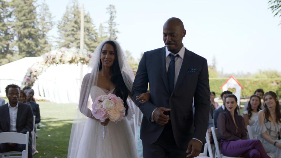 Kelly walks down the aisle on James's arm while Lena and Nia watch from the audience.