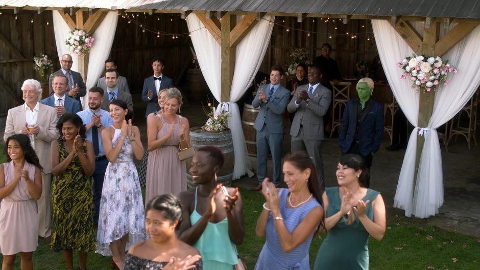 Winn, J'onn, and Brainy watch as Nia catches the bouquet.