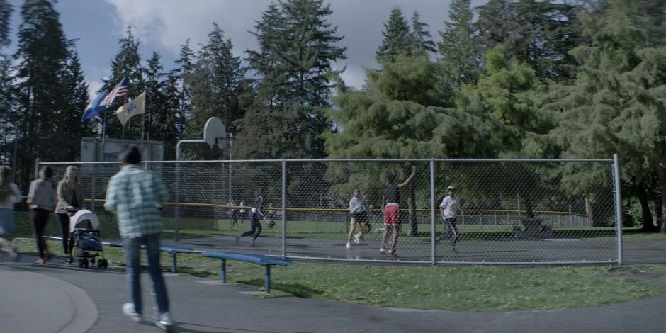 A group of teens play basketball in the park.
