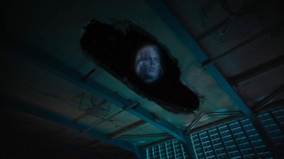 Naxim Tork's face appears in the sky through the whole in the roof of the gym.