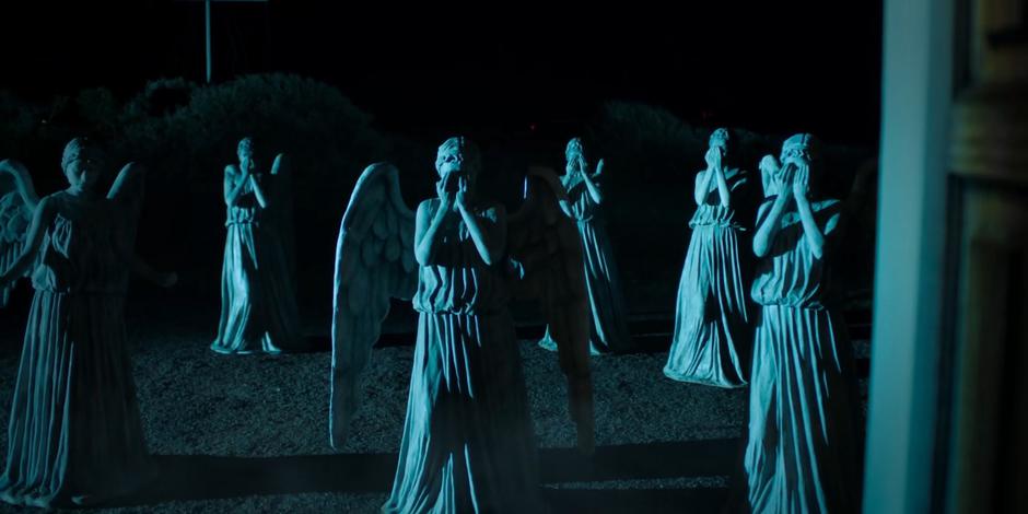 A group of Weeping Angels stand outside the front door of the house.