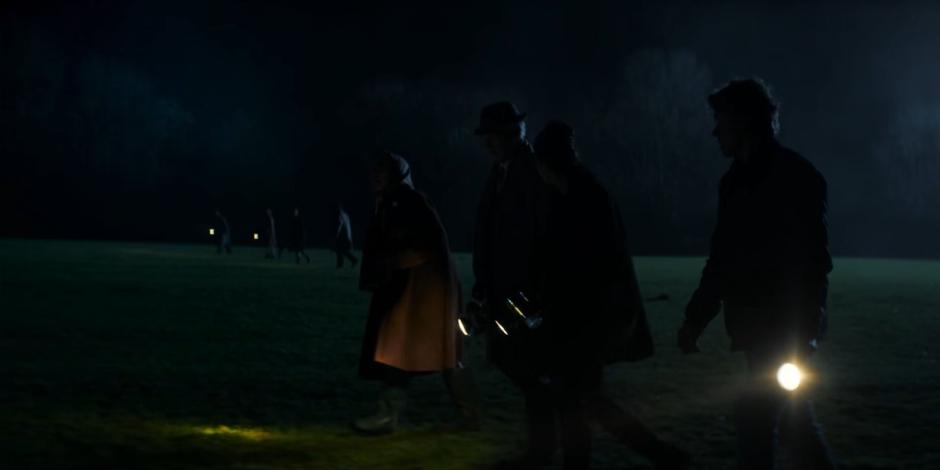 Jean, Gerald, Yaz, and Dan walk across the field with another search group in the distance.