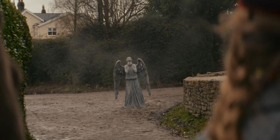 A Weeping Angel stands in the street ahead of Yaz, Dan, and Peggy.