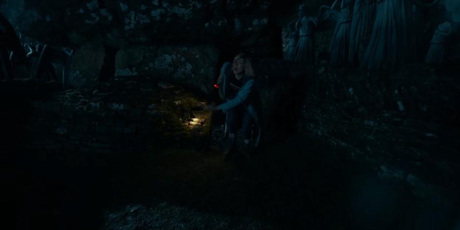 The Doctor climbs out of the tunnel into the ruins.