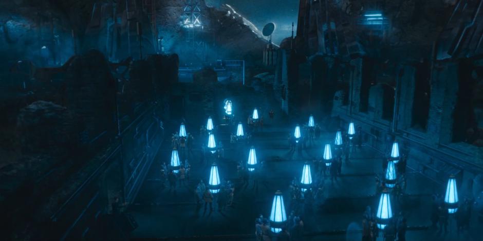 People stand in groups facing glowing crystals while Swarm, Azure, and the Passenger stand at the front of the ruins.