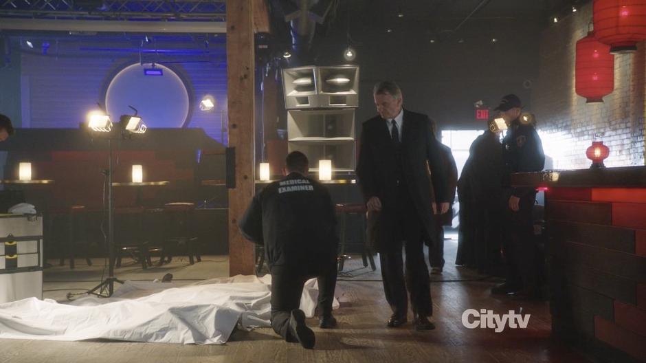 Hauser walks past the bodies in the club.