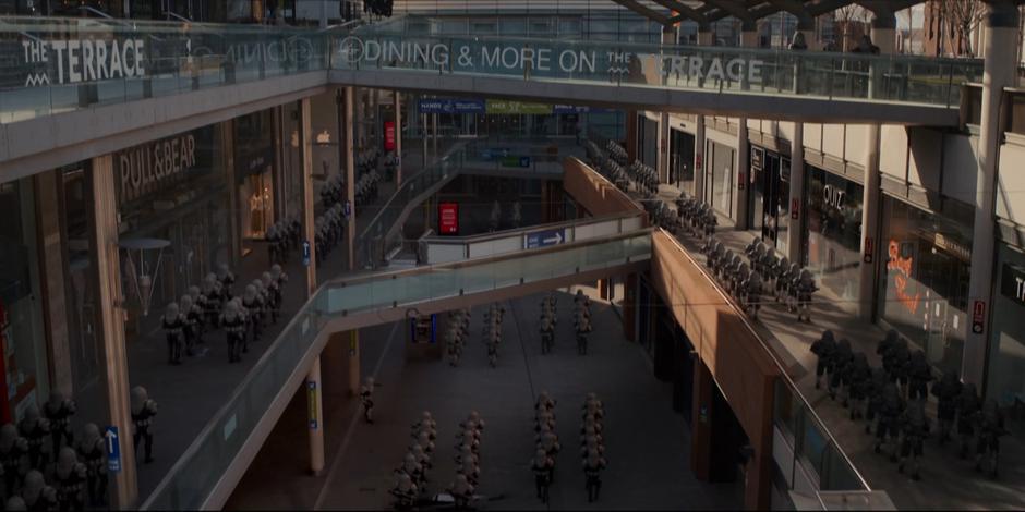 Dozens of Sontarans walk through the open-air mall.