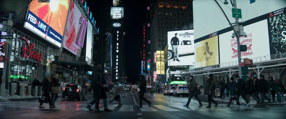 Clint crosses the street in Times Square at night.