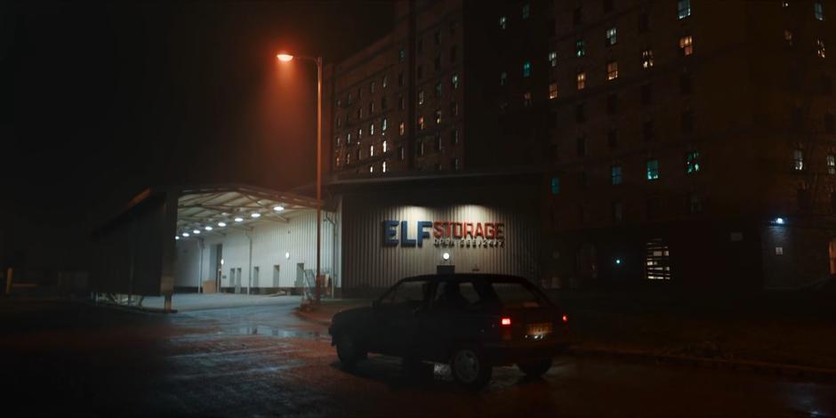 Nick parks his car in front of Elf Storage late at night.