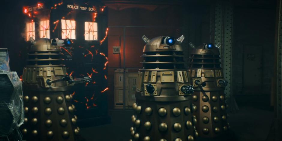 Three Daleks come around the TARDIS and control group.